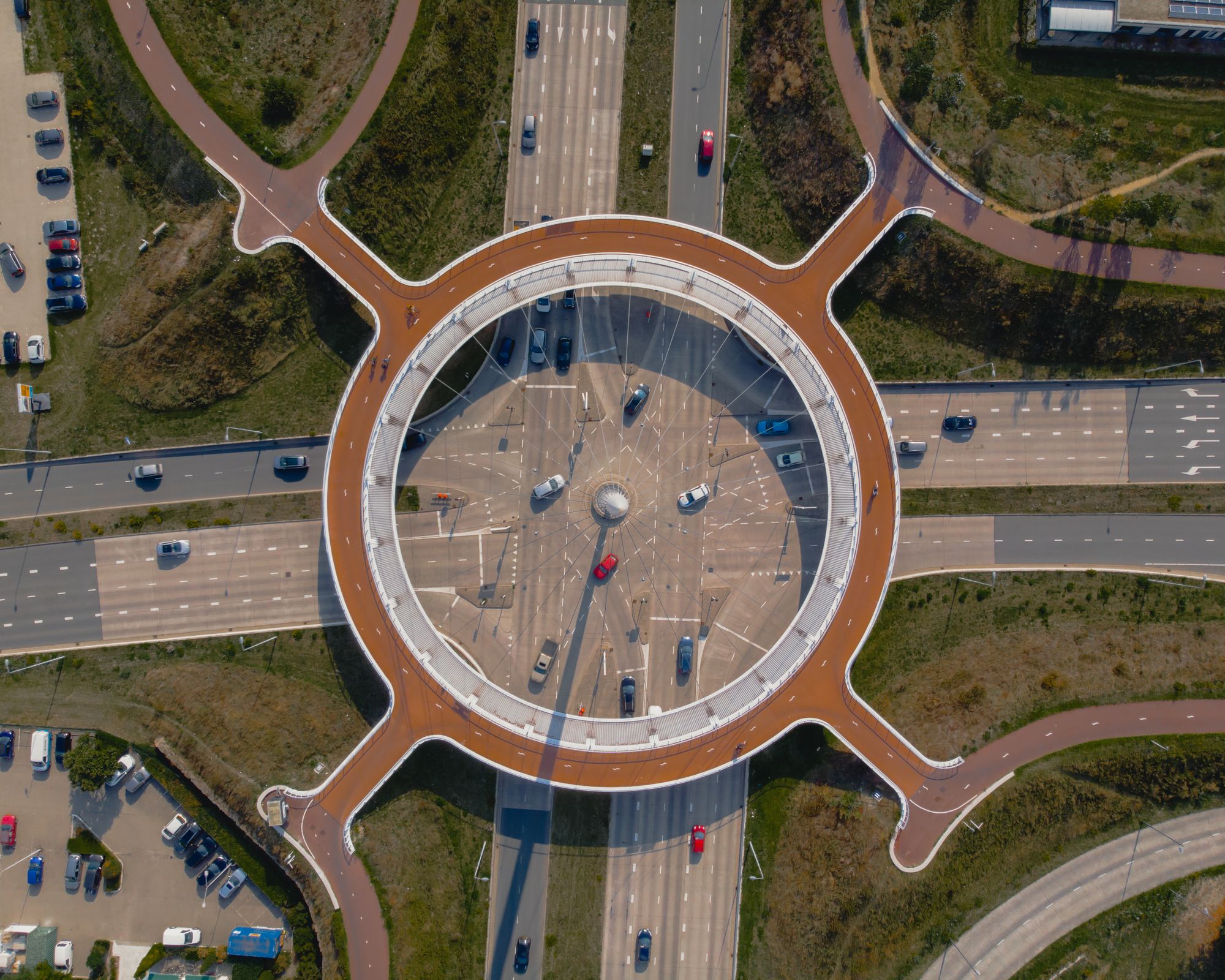Overhead photograph of an Eindhoven road junction with cars below a circular cycle bridge